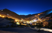 Nachtansicht von Saalbach-Hinterglemm mit beleuchteten Gebäuden und Bergen im Hintergrund.